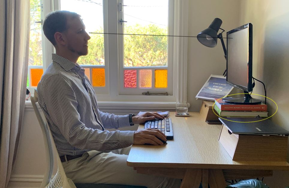 Worker at home workstation with straight line drawn from eye level to top of monitor screen indicating correct monitor height.